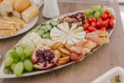Picture of cheese and fruit plate, including grapes and brie cheese, with bread off to the side.