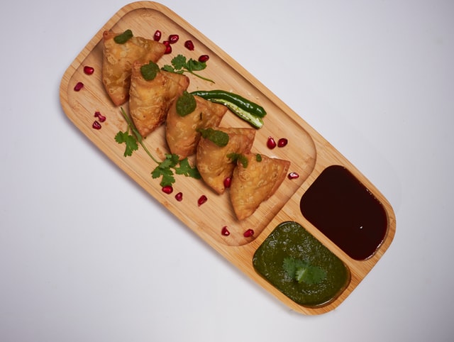 Top-down view of chicken triangles on serving board with dipping sauces. 