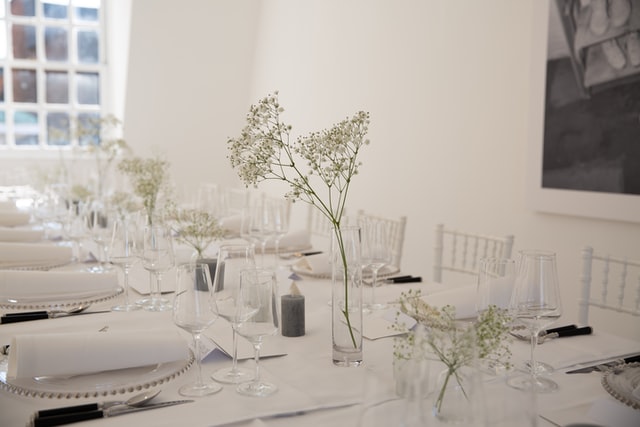 Flowers in clear glasses are part of this pristine, white table setting.