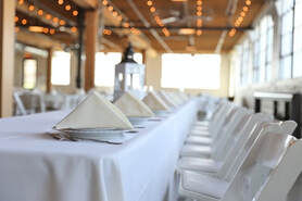 Picture of pristine wedding table setting with white table cloth, white chairs, and white folded napkins on plates.
